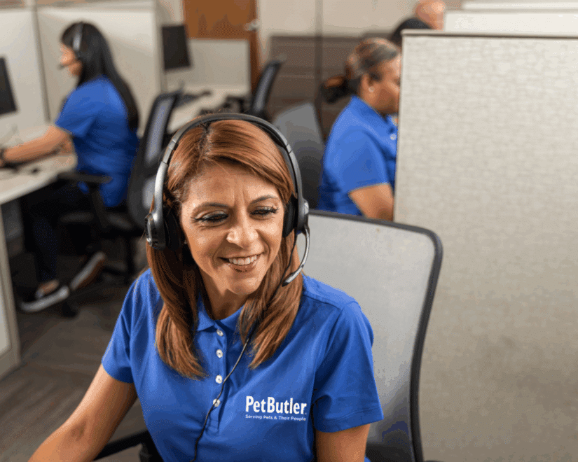 Woman from the Pet Butler call center smiling while wearing a headset and looking at her computer.