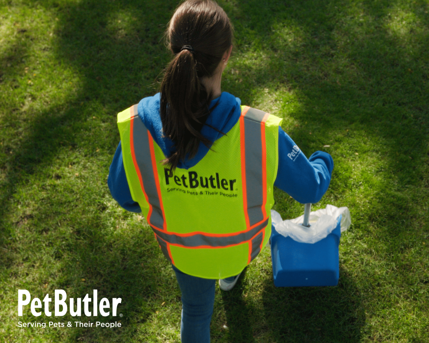 Pet Butler professional scooping dog waste in a customer’s yard.